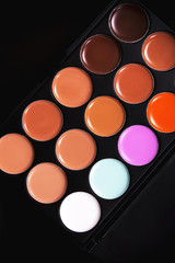 Palette concealer and correctors. Make-up base. Isolated on black background