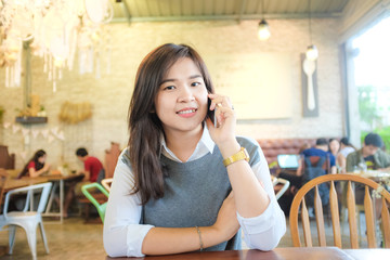 Beautiful asian young woman using cell phone while sitting at co