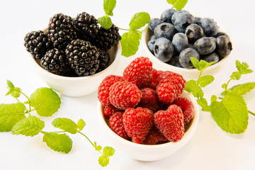 raspberries blackberries blueberries in plates on a table