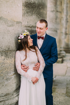 Young wedding couple embracing outside near atique building with columns