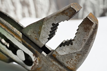 Macro detail of an old rusty pliers with its adjustable cogged head on the isolated background 