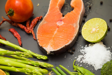 Fresh raw salmon filet with spicy herbs on black plate