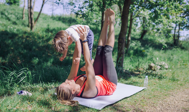 Mother doing exercise with kid on mat in park