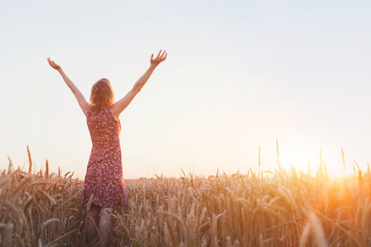 breathing, woman with raised hands enjoying sunset in the field