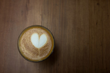 Cup of cappuccino art coffee with froth shape heart and wooden b
