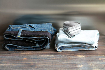 Denim jeans with belts stacked on a wooden board.
Wide panoramic. 