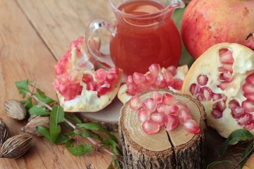 Ripe pomegranates with juice on wood background.