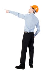 Back view of pointing young men in helmet. Curly businessman in a light jacket and a helmet shows his hand forward.