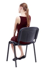 back view of young beautiful woman sitting on chair. Isolated over white background. A girl in a...