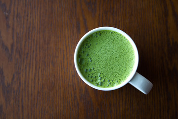 Matcha green tea in a white cup on wooden table