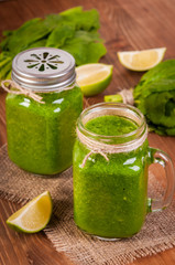 Jar mugs filled with green fresh organic spinach and lime lemon smoothie. Detox concept.