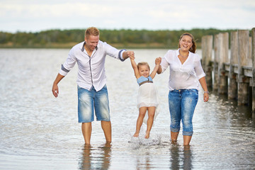 junge Eltern mit ihrer Tochter am See