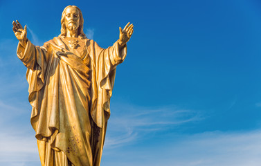 Old Jesus Christ golden statue over blue sky