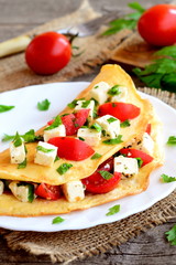 Stuffed omelette on a plate. Omelet stuffed with fresh tomatoes, red pepper and parsley. Eggs breakfast menu. Vintage style. Closeup
