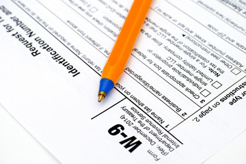 Application form W-9, Request for Taxpayer Identification Number (TIN) and Certification with ballpoint pen.