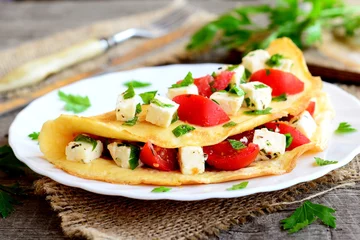 Outdoor-Kissen Home stuffed omelet on a plate. Egg omelet stuffed with tomatoes, cheese and green parsley. Vegetarian diet breakfast recipe. Fork, knife, cutting board on wooden background. Closeup © onlynuta