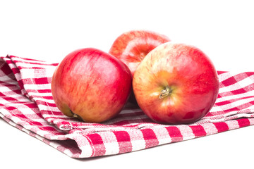 three ripe red apples on a towel