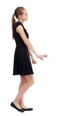 Naklejka premium back view of walking woman. Isolated over white background. Blonde in a short black dress is smiling.