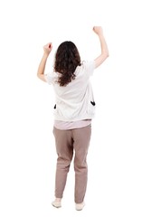 back view of dancing young beautiful woman. Long-haired curly girl happily waving his hands.