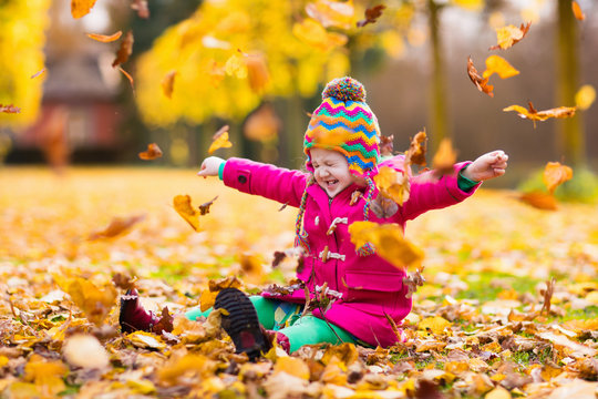 Little girl playing in autumn park