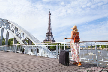 travel to Paris, Europe tour, woman with suitcase near Eiffel Tower, France.