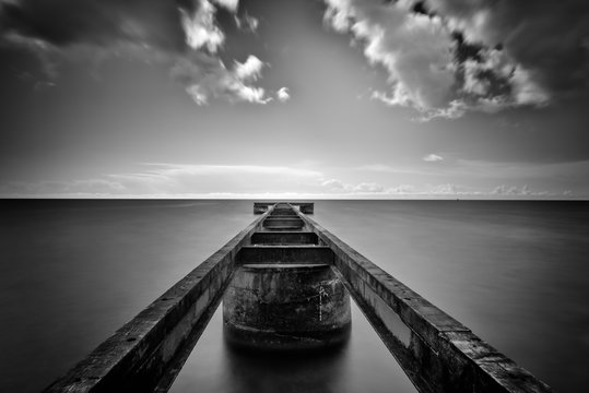 Jetty over sea with dramatic sky, Svarte, Skane County, Sweden, black and white 