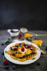 Homemade Belgian waffles with fresh ripe  berries served on white plate.
