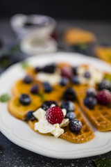 Homemade Belgian waffles with fresh ripe  berries served on white plate.
