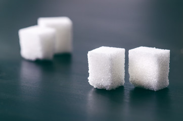Cubes of sugar on a dark background. Unhealthy ingredients. Lump sugar