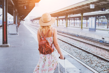 summer travel, woman with suitcase waiting for  her train on platform of railway station