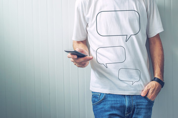 Guy with speech balloons printed on shirt using mobile phone