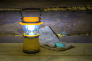 Luminous hand lantern standing on the shelves near mitten and soap.