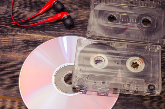 Retro compact cassette with disc and headphones on wood.
