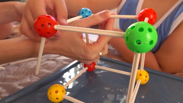 Little boy and his mum playing with colorful plastic construction set. Molecule models. 4K close up video