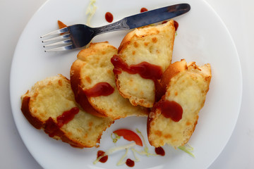 Garlic and herb bread slices with tomato sauce in white plate.