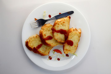 Garlic and herb bread slices with tomato sauce in white plate.
