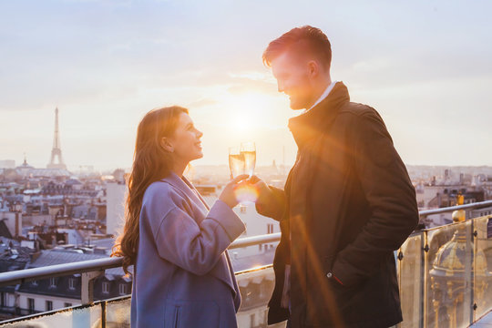 happy couple drinking champagne and smiling at sunset in Paris, celebration