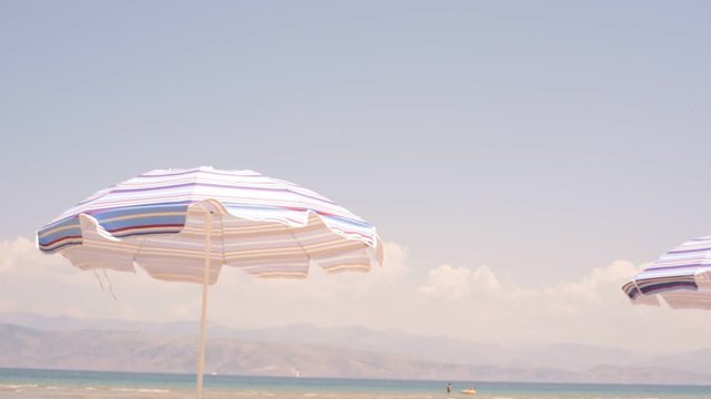 A sun lounger parasol flutters in the wind at the beach