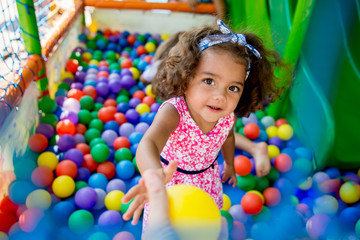 Fototapeta na wymiar Happy little girl sitting in colourful balls