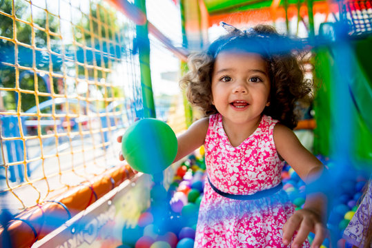 Happy little girl sitting in colourful balls