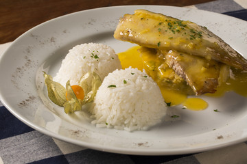 fried tilapia served with rice on white plate.