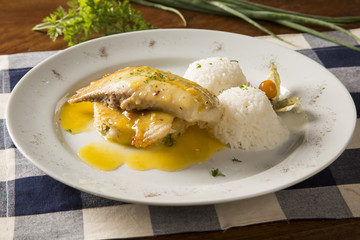 fried tilapia served with rice on white plate.