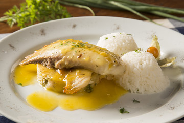 fried tilapia served with rice on white plate.