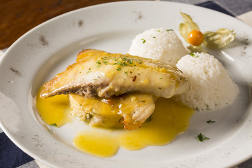 fried tilapia served with rice on white plate.