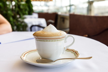 Sasha cappuccino stands on a saucer with a spoon.