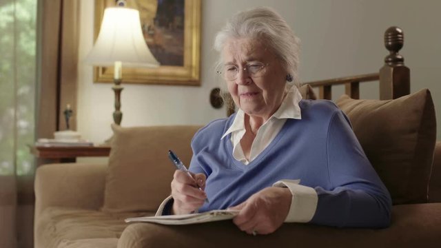 A senior elderly woman on a couch suffers dementia or Alzheimer's and can't remember something. Shot in 4K UHD.