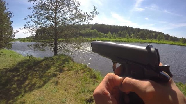 Hand with Gun Triggers in Forest near River