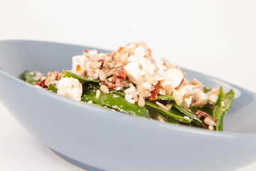 Spinach, dried tomatoes, feta cheese and sunflower seeds salad on a white background