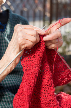 Senior woman hands knitting with red wool
