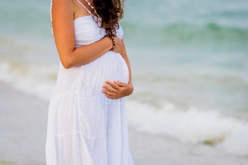 Fototapeta na wymiar Side view midsection of a pregnant woman touching tummy against ocean